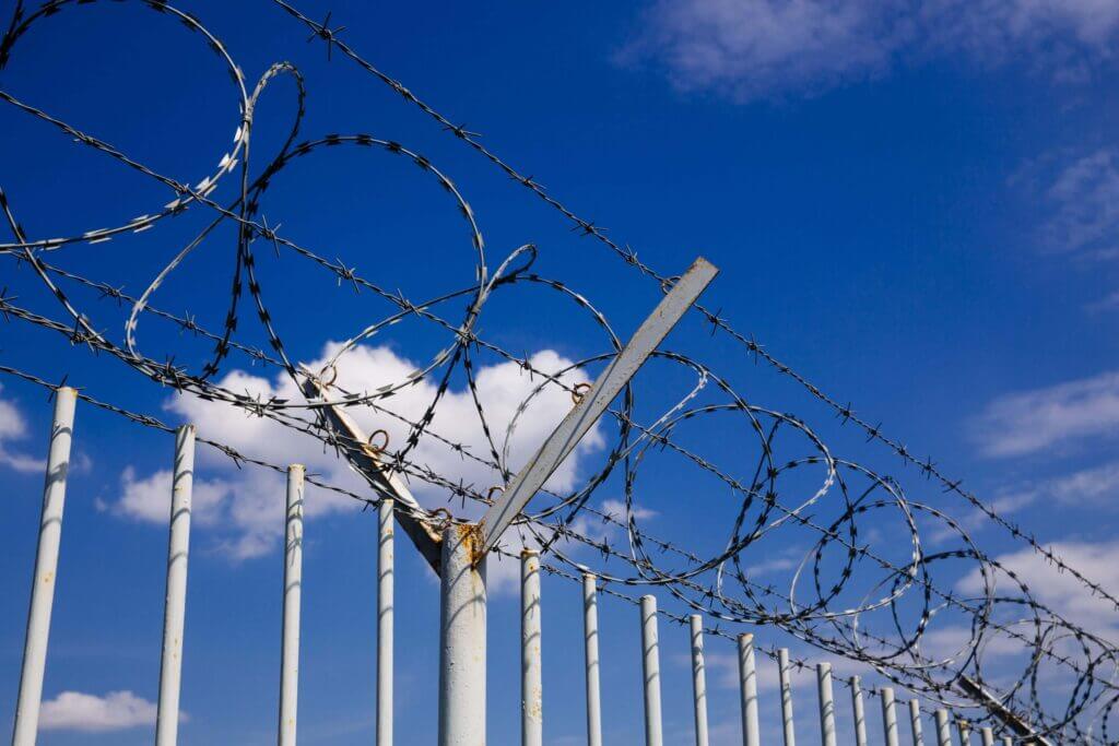 Barbed wire wall with sky in the background